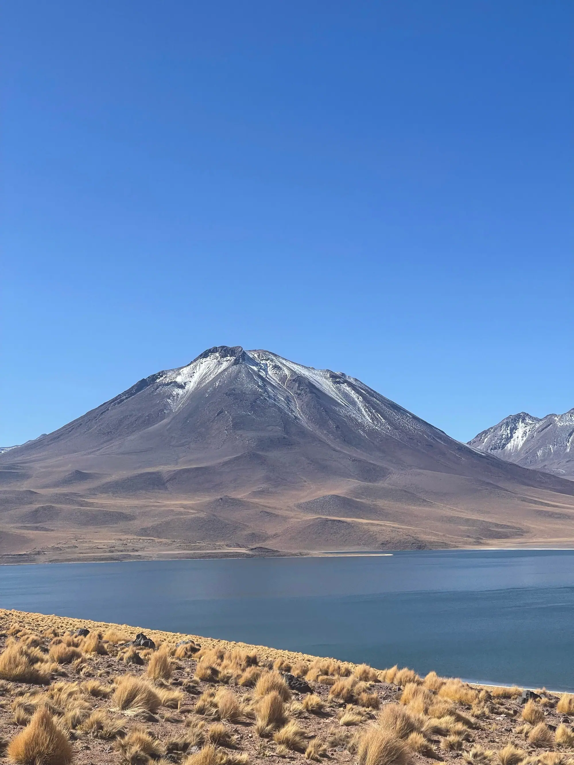 Snow-dusted volcano and a high-altitude lake on the Atacama plateau
